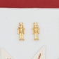 Gold-toned nutcracker stud earrings displayed on a white card alongside decorative star-shaped ornaments, with a red and white background.